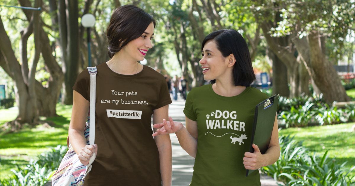 A pet sitter and dog walker are walking on a sidewalk talking to one another