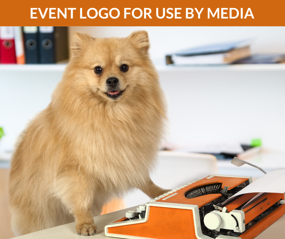 A small dog poses for a photo by a typewriter.