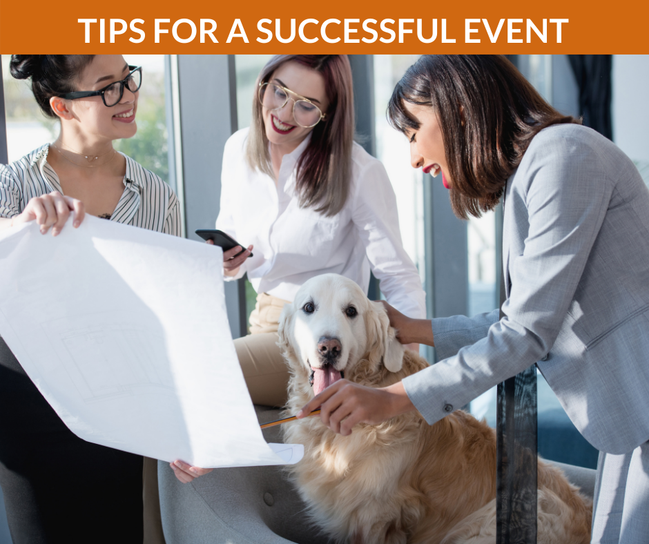 Smiling women pet a dog in an office while looking at a blueprint.